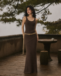 Model wearing dark brown ribbed knit maxi dress with rope belt, editorial outdoor setting