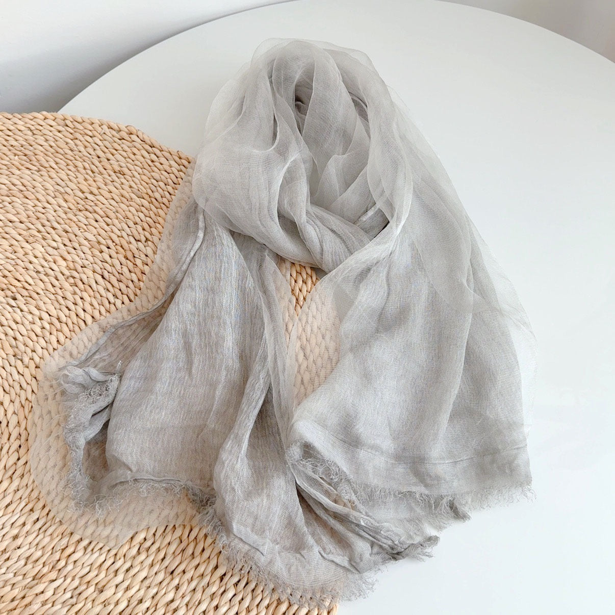 Lightweight Gauze Scarf in Grey — flat lay on rattan